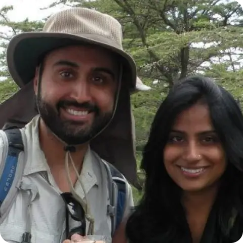 Sameer and Nita smiling outdoors, dressed in adventure gear.